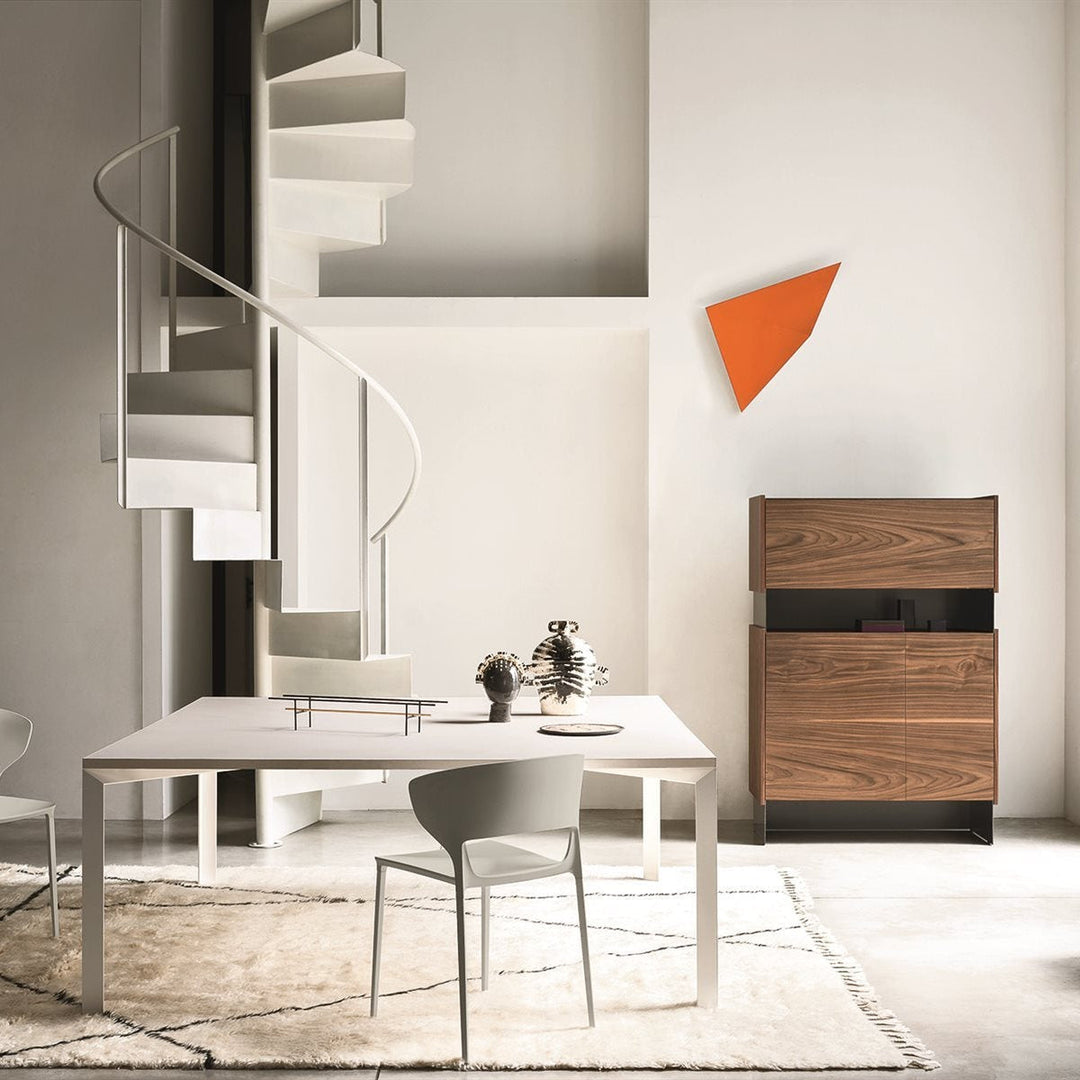 Desalto Koki chair in matte finish beside minimalist white table, spiral staircase, and walnut cabinet