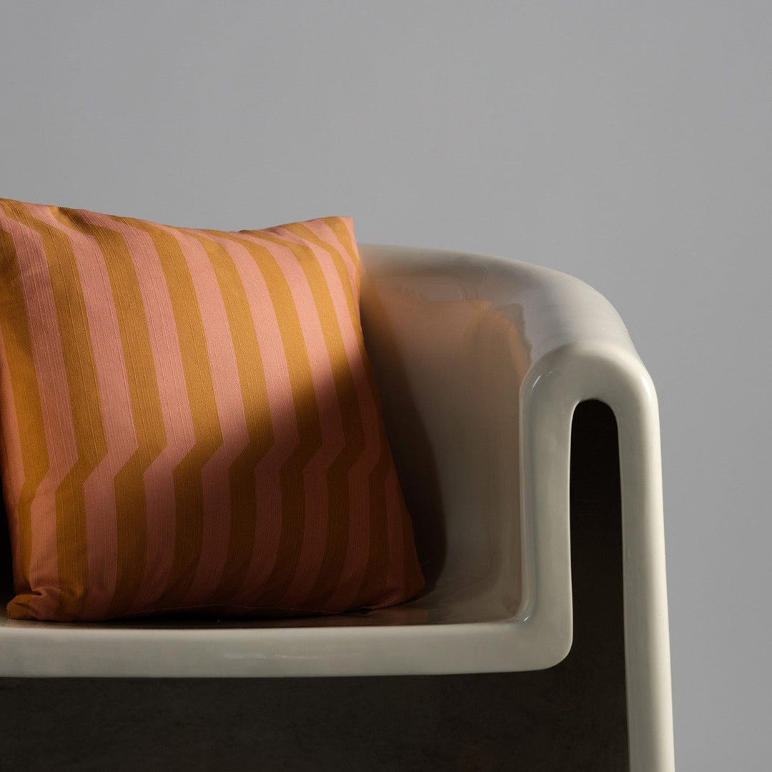 Glossy clay accent chair with curved lines, featuring a striped geometric cushion