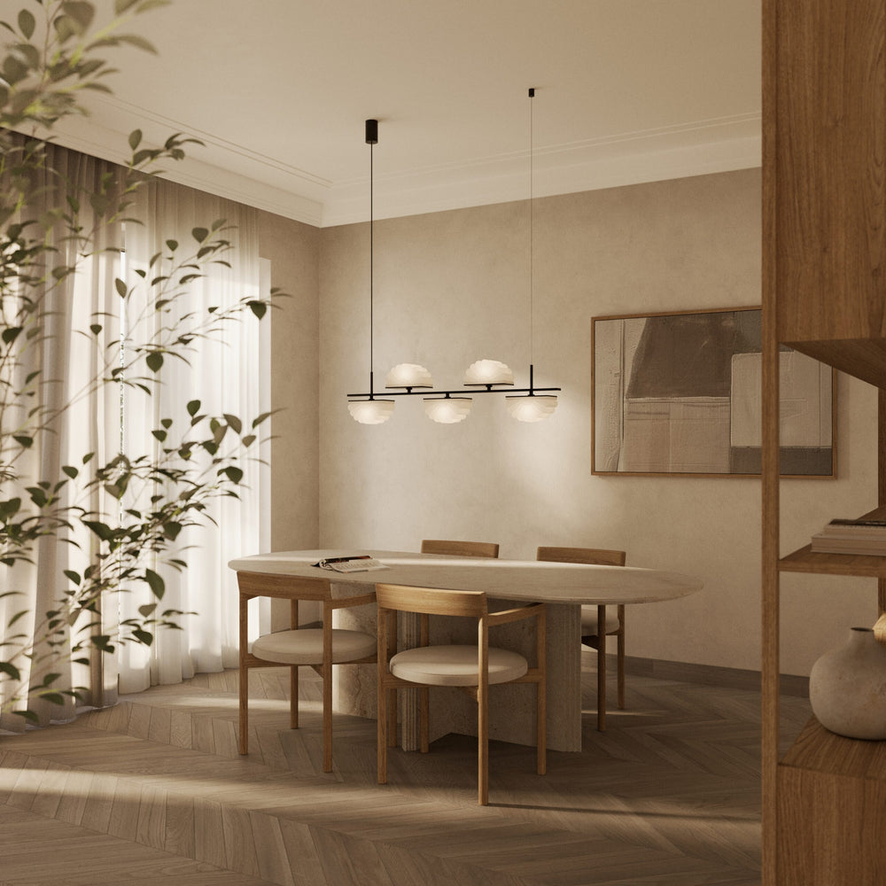 Gina Linear Pendant Linear Pendant lit over an oval dining table with wooden chairs in a sunlit room