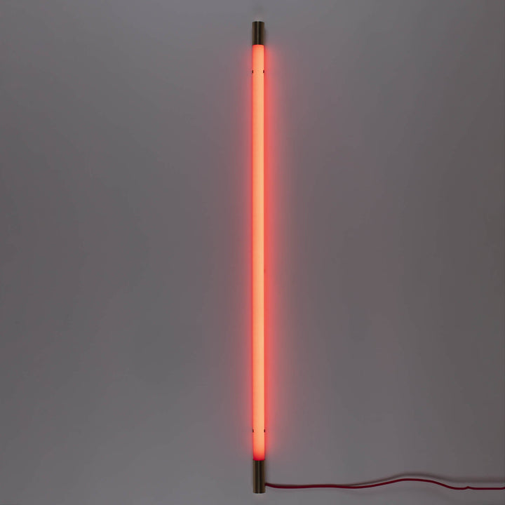 Seletti Linea Golden End Red, red tube glowing upright against a gray wall