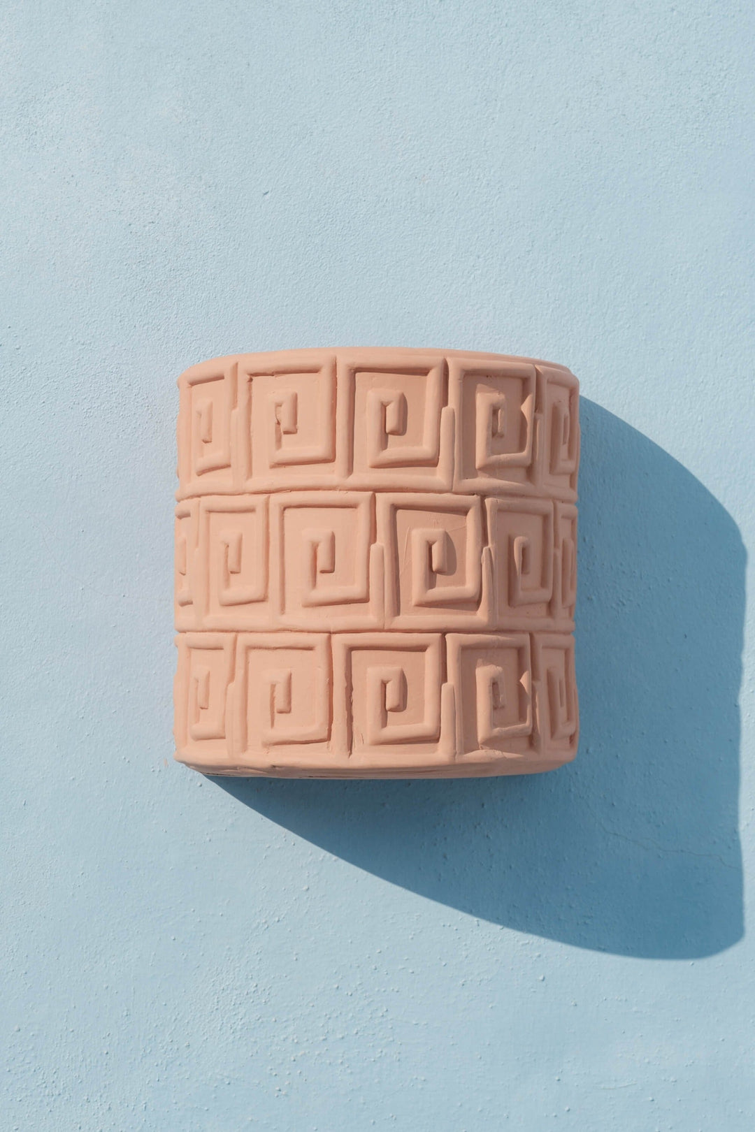 Seletti Magna Graecia Terracotta Wall Vase Greche, the vase hung on a pale blue wall, casting a shadow