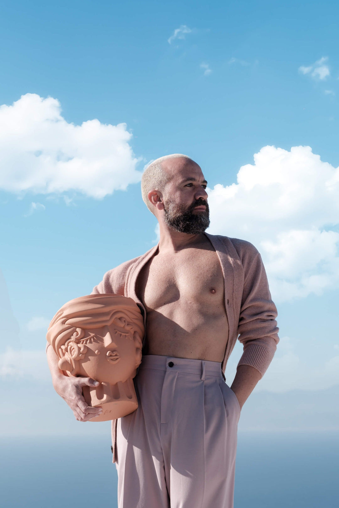 Seletti Magna Graecia Terracotta Head Vase Woman, a man holding the woman head vase by the sea