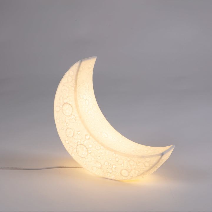 Seletti My Tiny Moon Lamp, the moon lamp lit warm against a gray backdrop