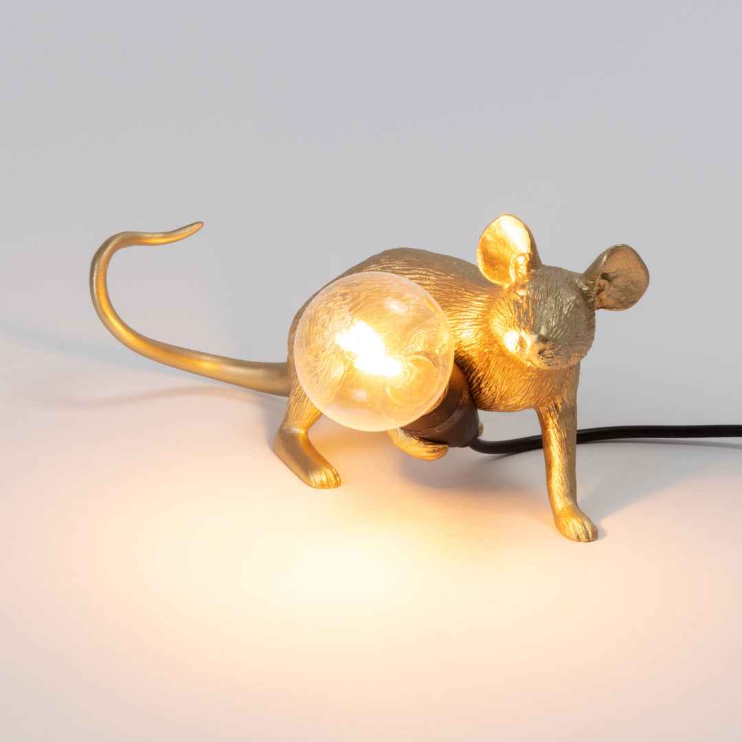 Seletti Mouse Lamp Lop Lying Down Gold, the lamp switched on, the bulb glowing warm in the mouse&