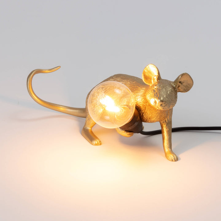Seletti Mouse Lamp Lop Lying Down Gold, the lamp switched on, the bulb glowing warm in the mouse&