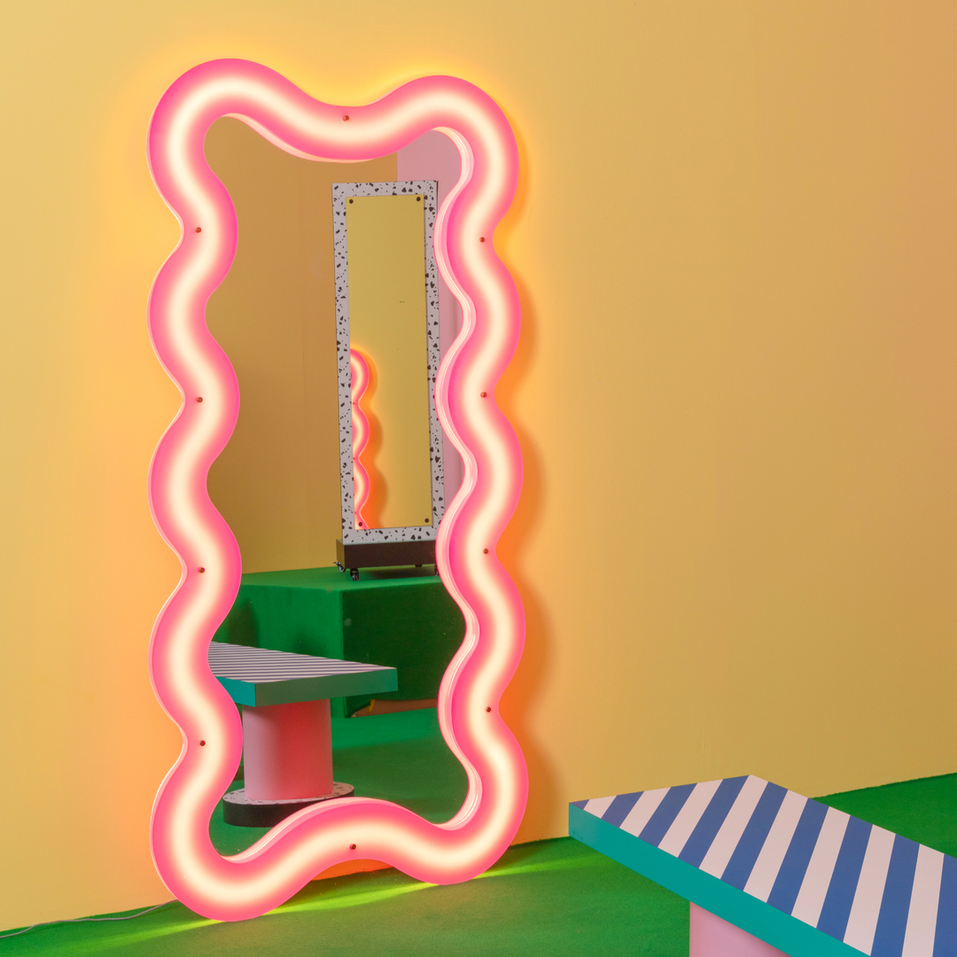 Seletti Supercurve Wavy Mirror Tall, the tall mirror glowing pink, leaning against a yellow wall