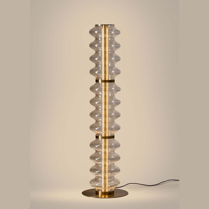 Vitree Floor Lamp lit, warm LED glow running through the clear wavy glass column