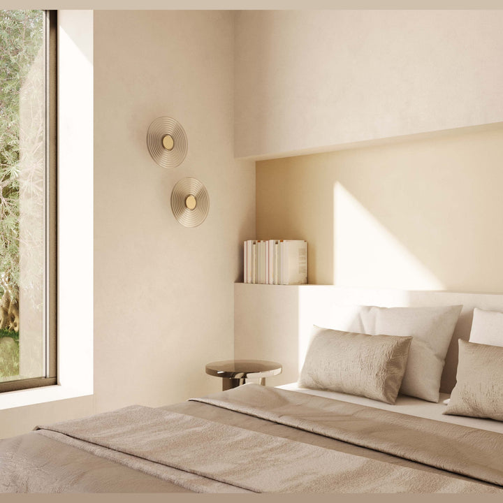 Two Glic Wall Lamps on a cream wall above a bed in a sunlit bedroom
