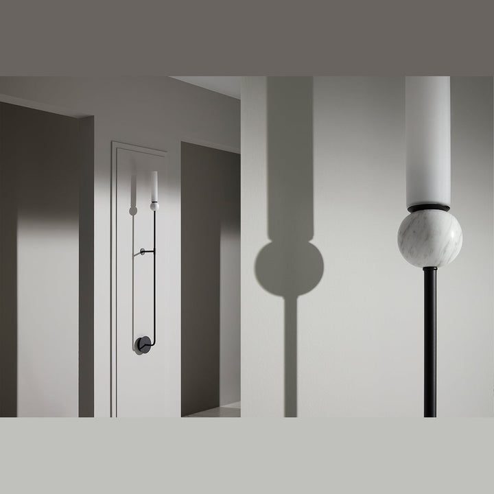 Close-up of a white marble and matt black Delie Wall Lamp casting a shadow on a grey wall