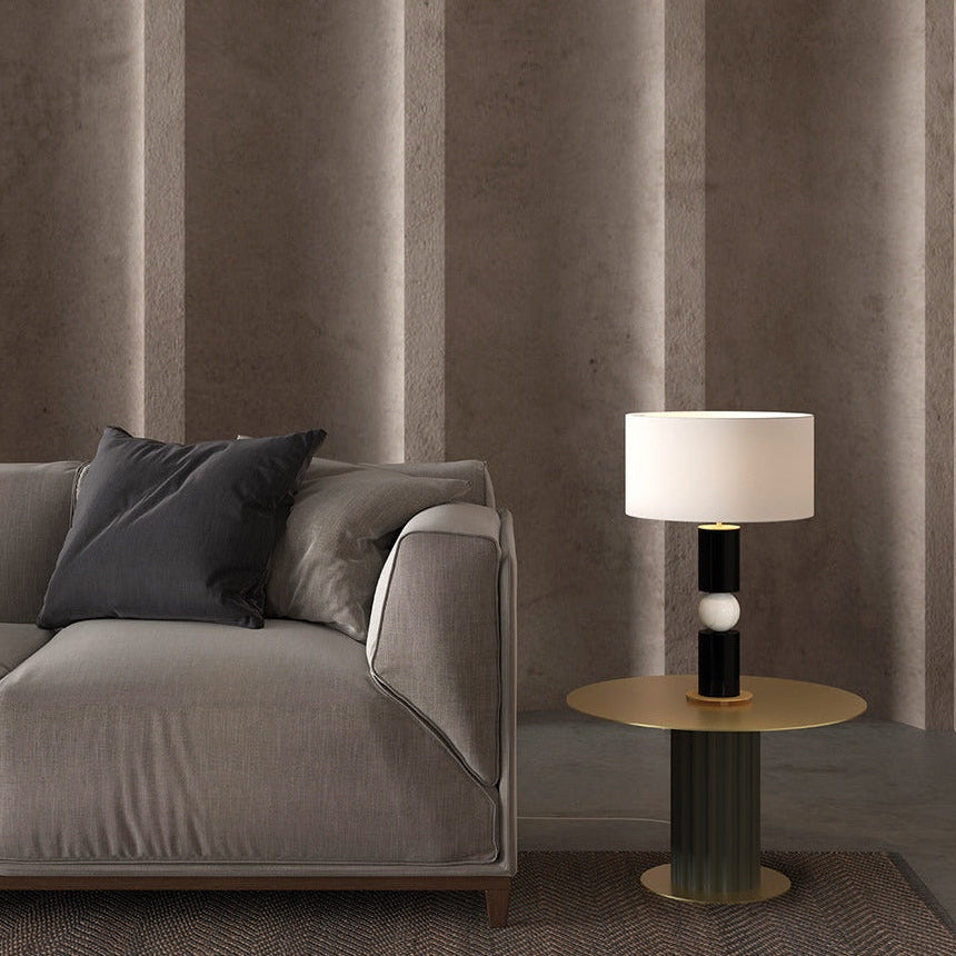 Alda Table Lamp lit on a brass side table beside a grey sofa