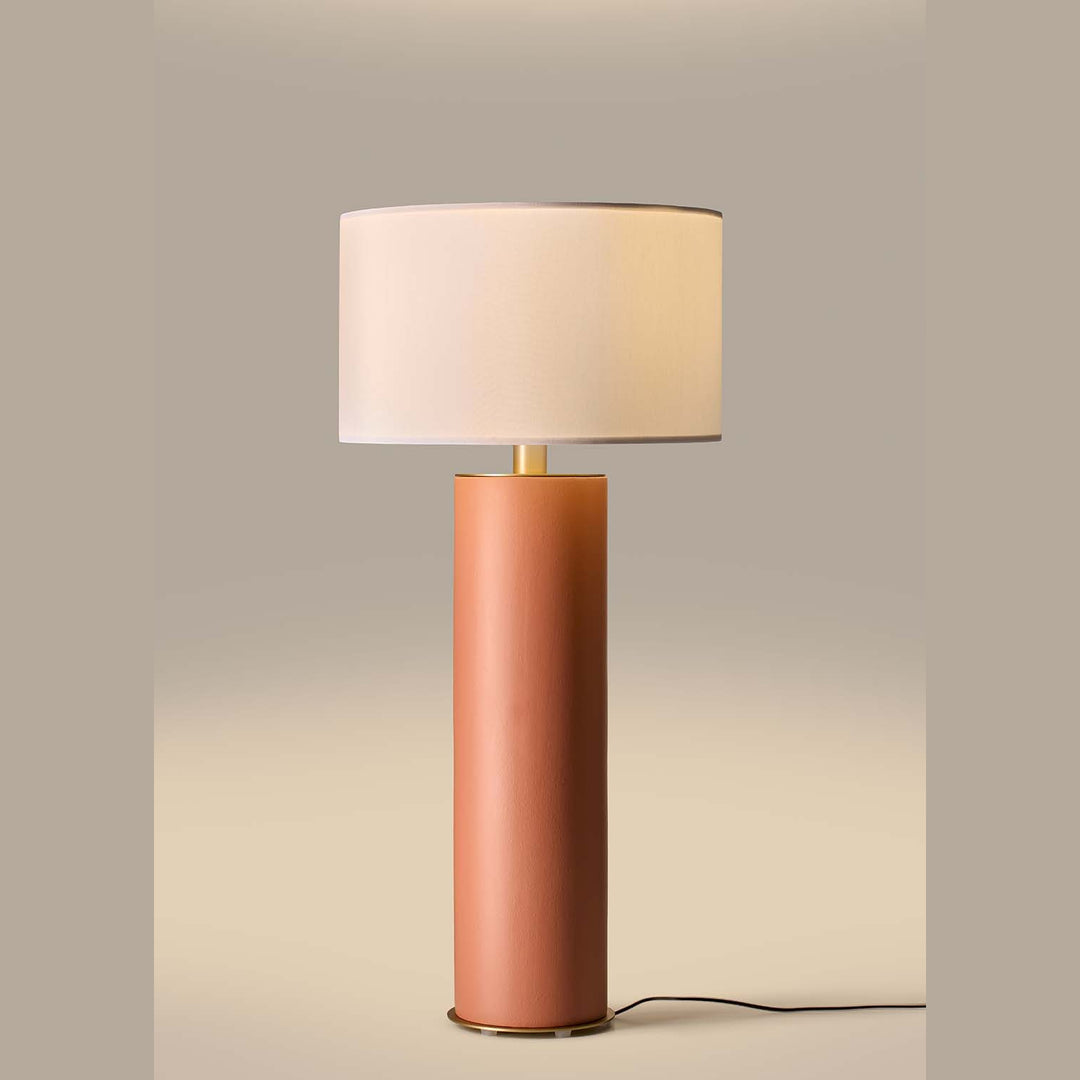 Amec Table Lamp lit, white drum shade glowing above a terracotta ceramic column on a warm beige backdrop