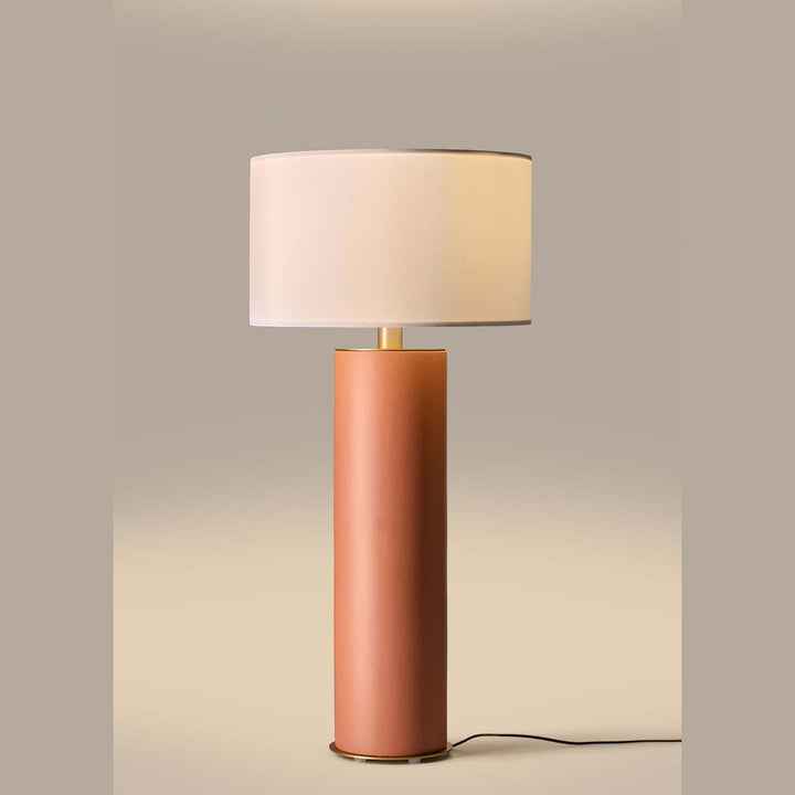 Amec Table Lamp lit, white drum shade glowing above a terracotta ceramic column on a warm beige backdrop