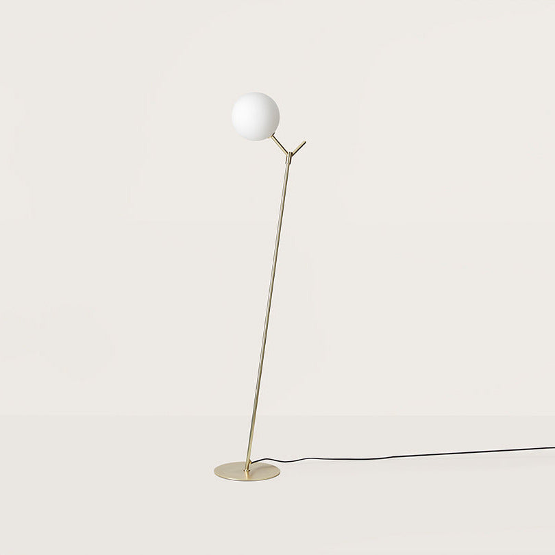 Atom Floor Lamp with an opal glass globe on a slim angled matt brass stem and round base, by Aromas del Campo
