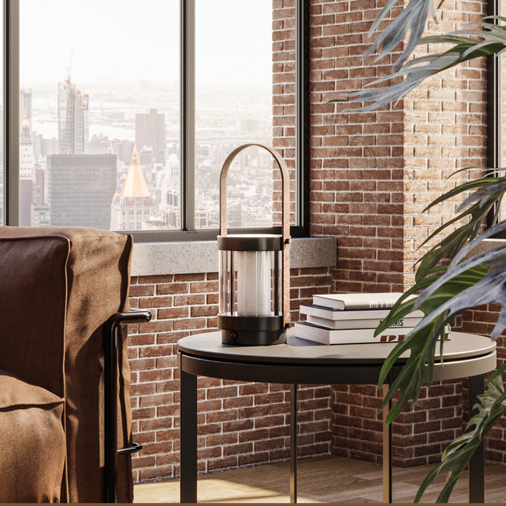 Bally Table Lamp on a round side table with books beside a leather armchair in a brick-walled city loft