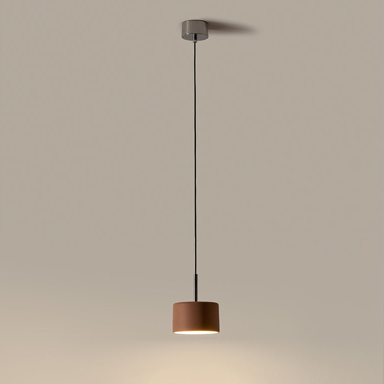 Cora Pendant Lamp lit, a rust brown ceramic drum casting a warm pool of light