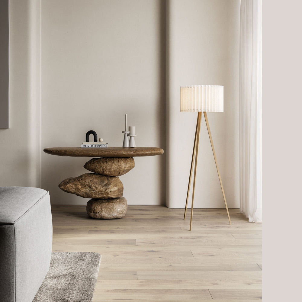 Dira Floor Lamp beside a stacked-stone console table and grey sofa in a neutral living room