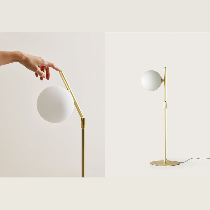Hand adjusting the angled brass arm of the Endo Table Lamp, with the full lamp alongside