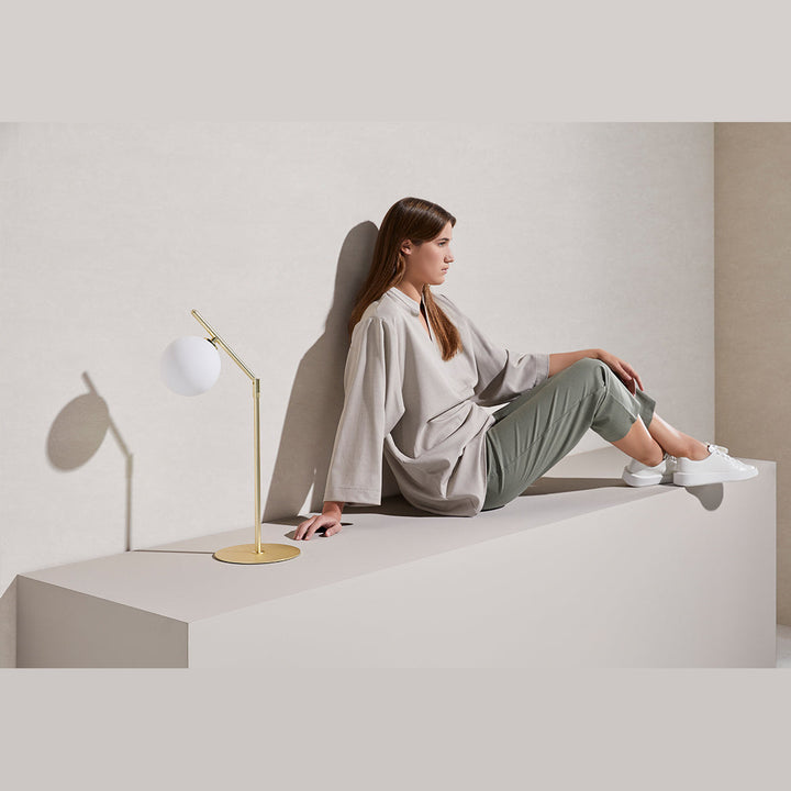 Brass Endo Table Lamp on a white bench beside a seated woman