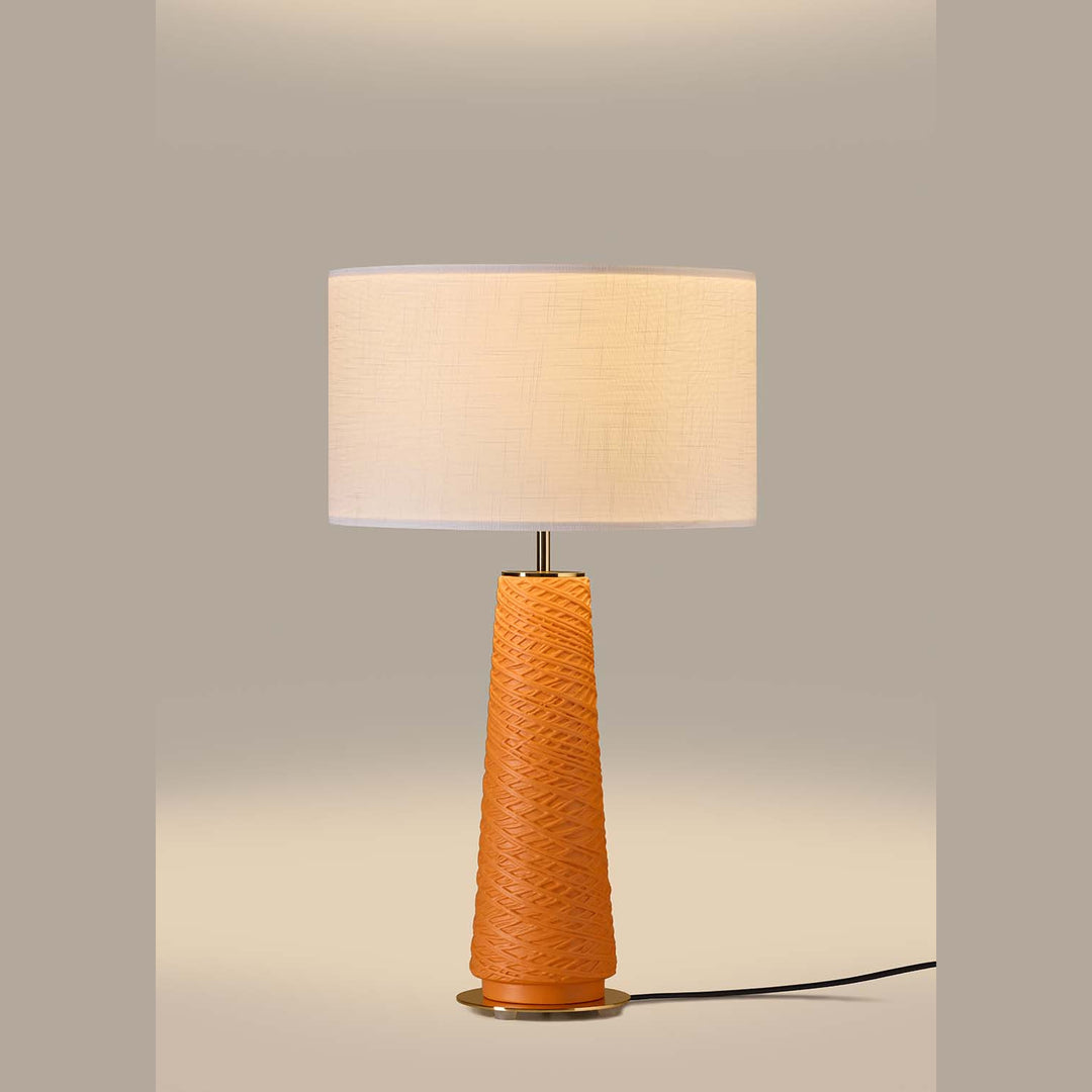 Fill Table Lamp lit, orange woven-texture ceramic base under a glowing linen drum shade