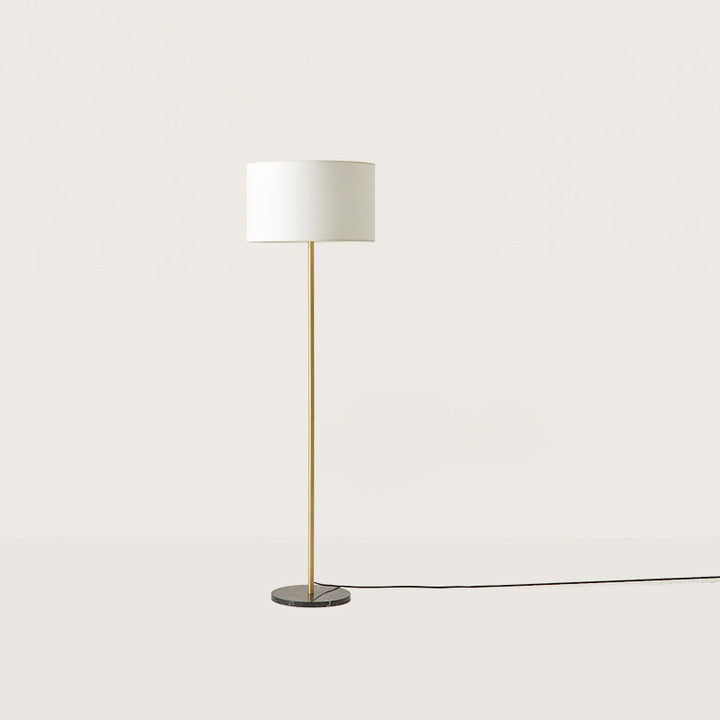 Hedra Floor Lamp with a slim brass stem, black marble base and white drum shade, unlit, by Aromas del Campo