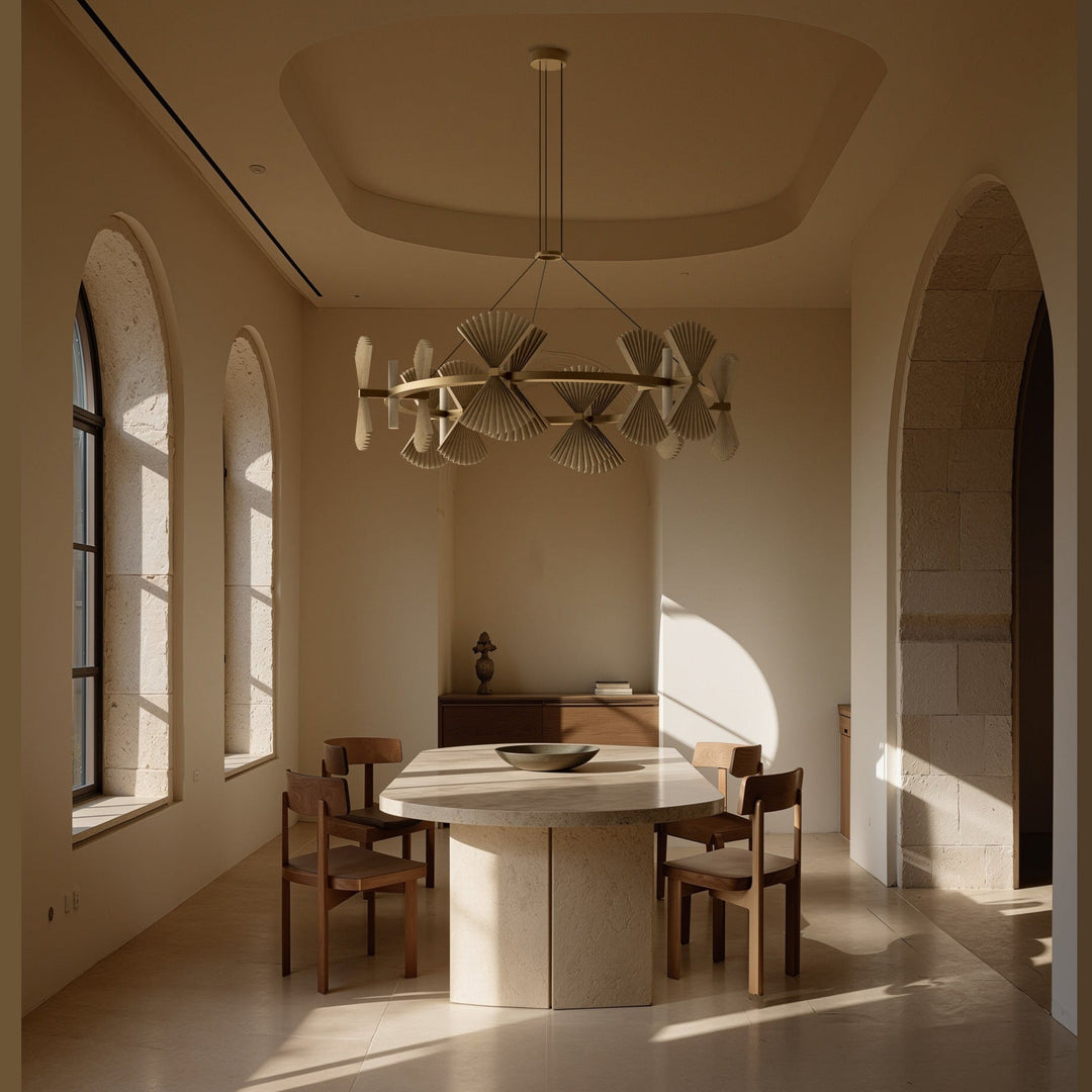 Hita Chandelier Chandelier above a stone dining table with wooden chairs in a sunlit arched room