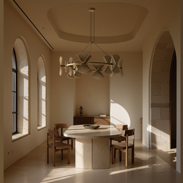 Hita Chandelier Chandelier above a stone dining table with wooden chairs in a sunlit arched room