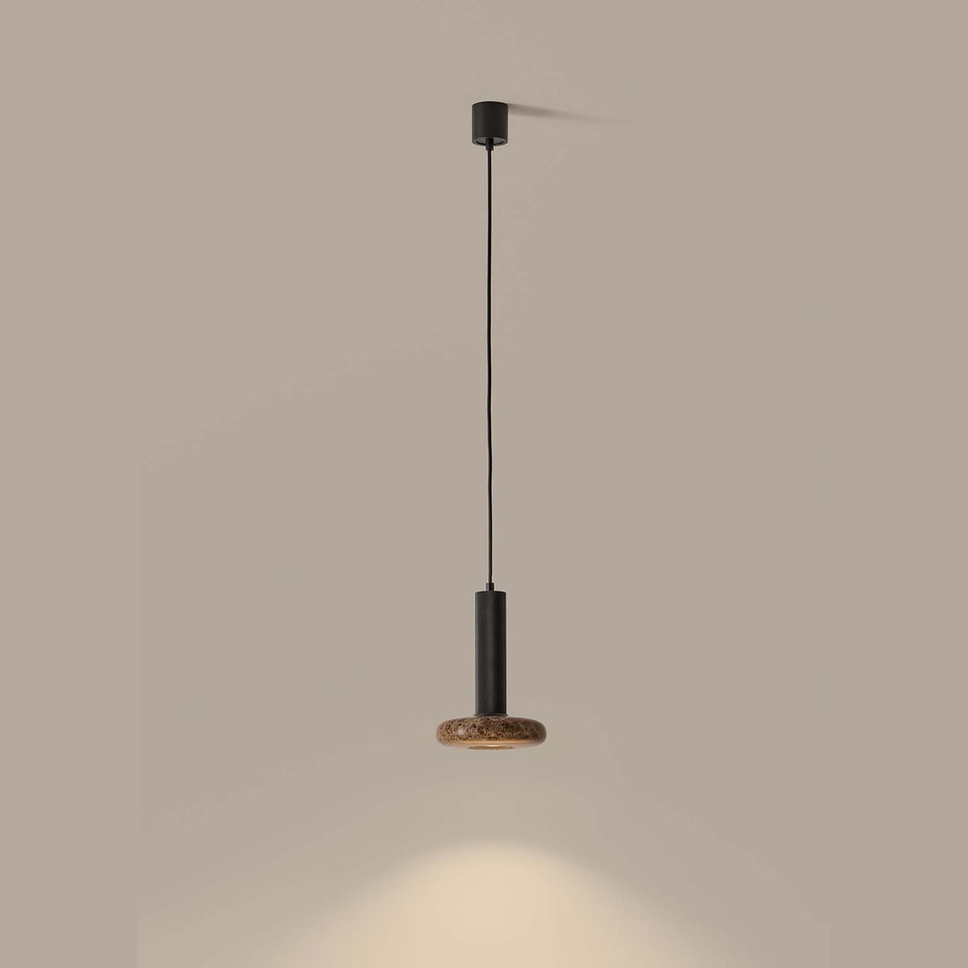 Hulo Pendant Lamp with brown marble disc, lit and casting a pool of light on the wall