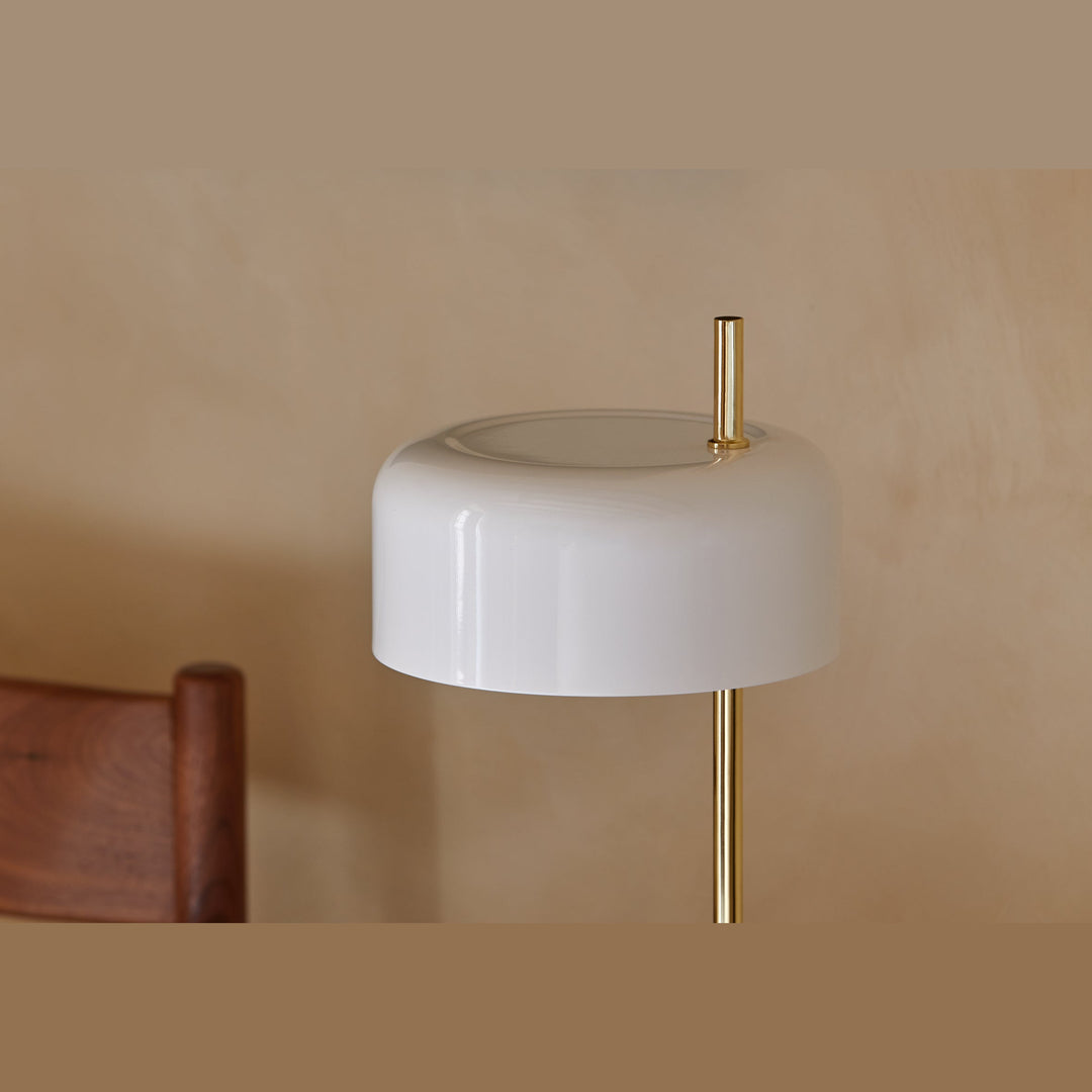 Close-up of the glossy white ceramic shade and brass stem