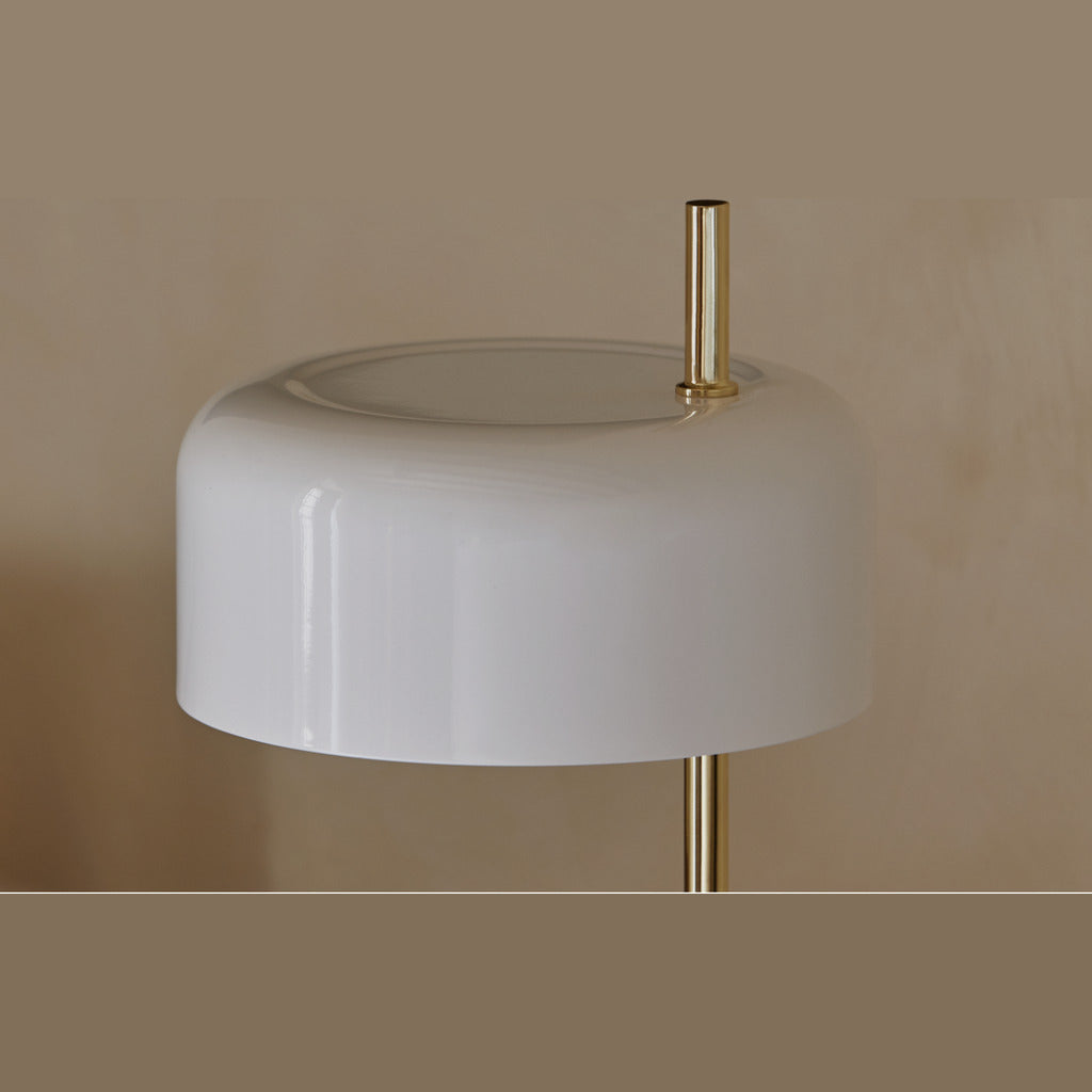 Close-up of the white ceramic shade glowing on its brass stem