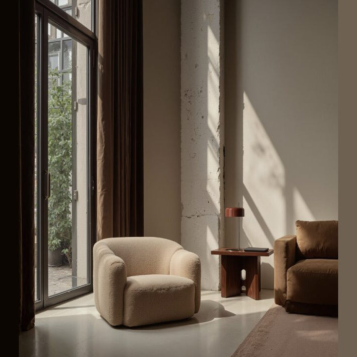 Red-shade version on a side table between two bouclé armchairs near tall windows