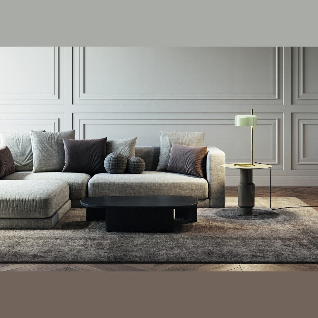 Wide living room with low sofa, black coffee table and the pale-green-shade lamp on a side table