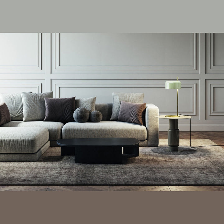 Wide living room with low sofa, black coffee table and the pale-green-shade lamp on a side table