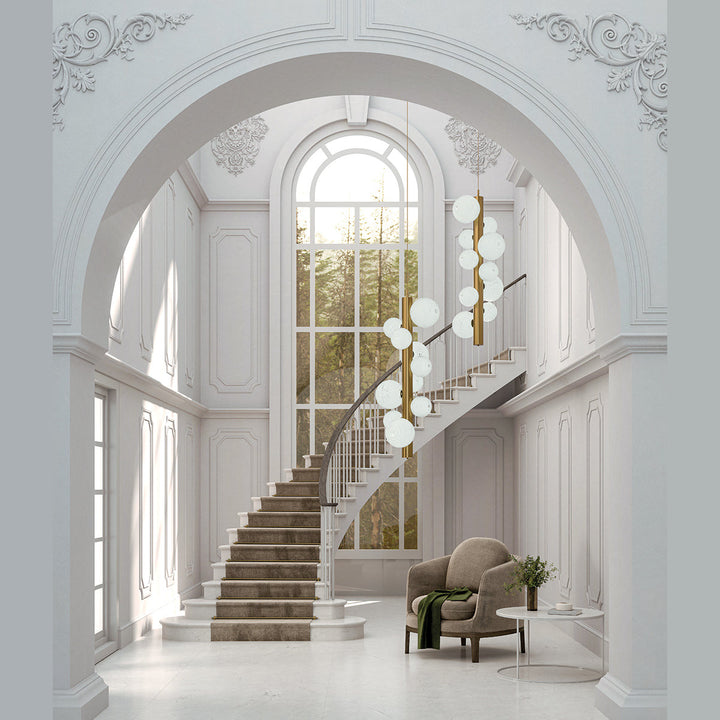 Two vertical Lera Pendant Lamps with opal globes hanging in a grand stairwell with arched window