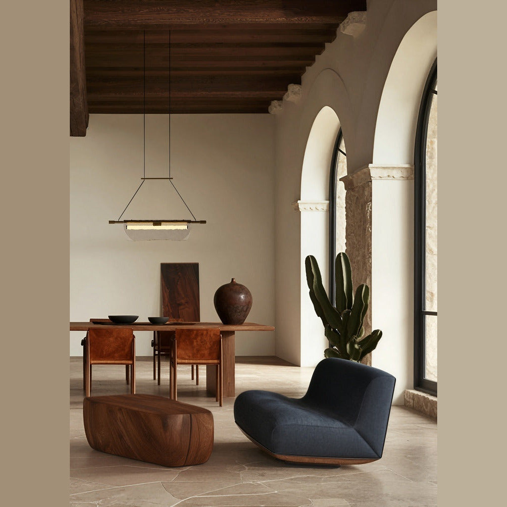 Lida Linear Pendant, Single size, above a wooden dining table in an arched room with a navy lounge chair