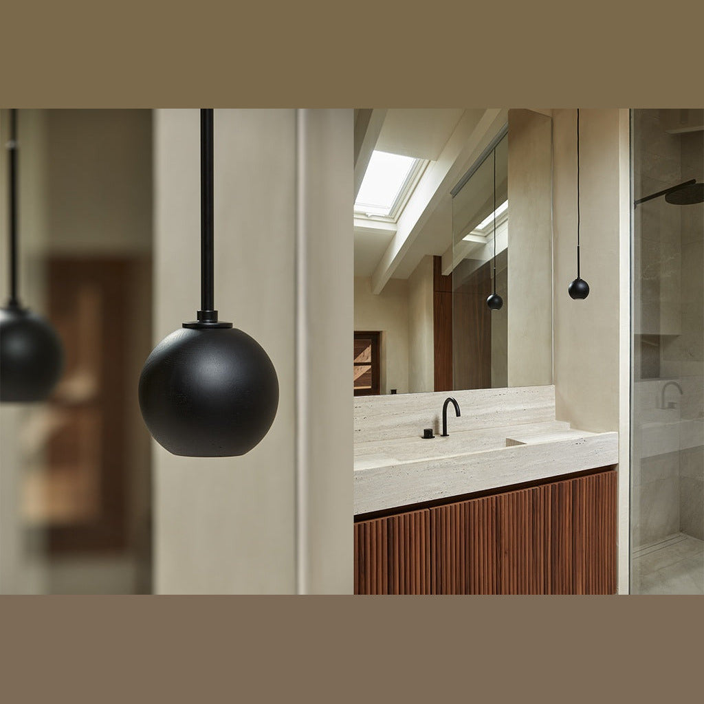 Lita Pendant Lamp close-up of a matt black sphere with a stone bathroom vanity behind