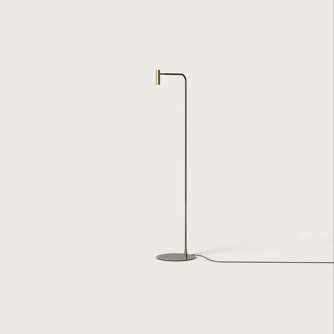 Maho Floor Lamp, slim black stem curving to a small brass cylinder spotlight head, by Aromas del Campo