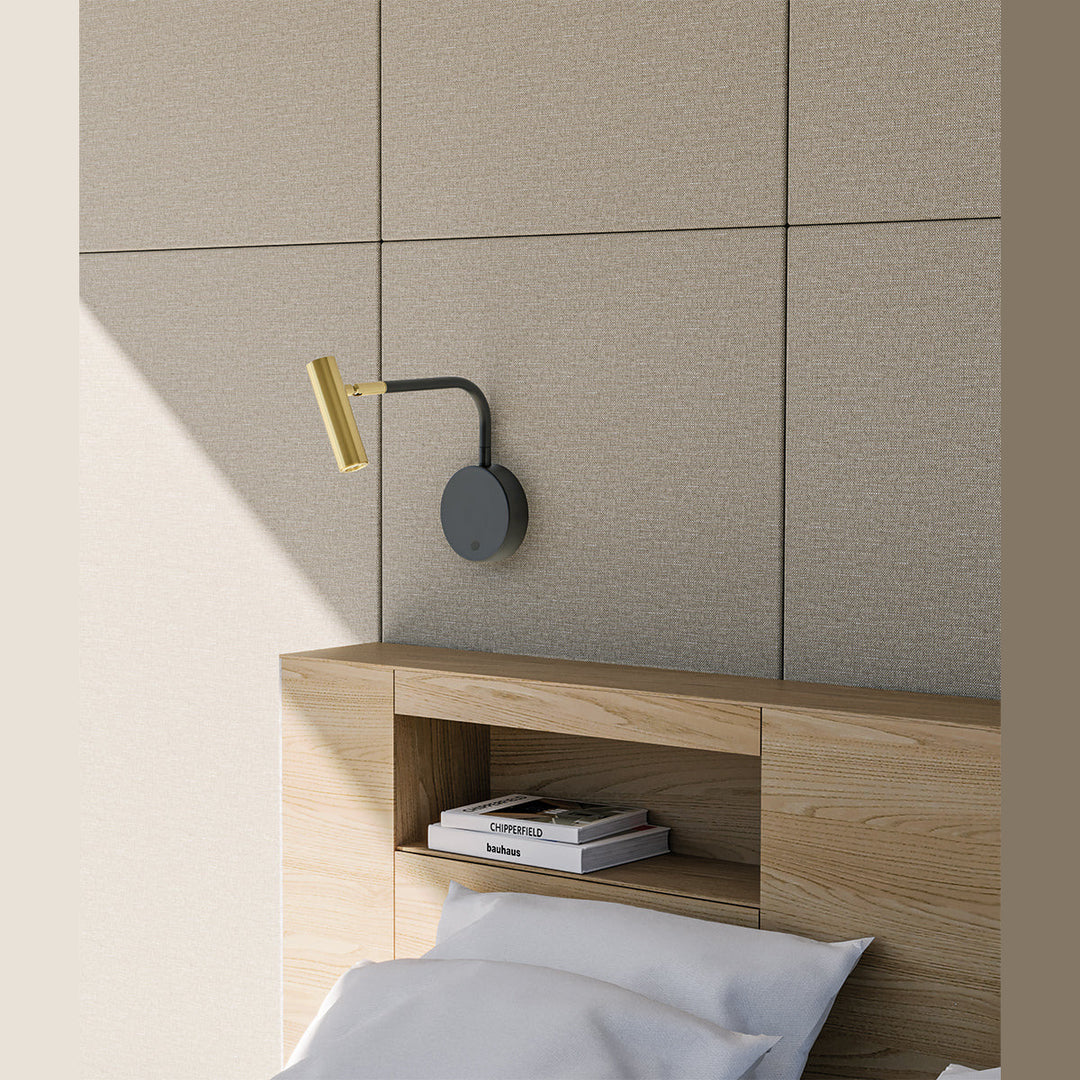 Maho Wall Lamp with brass head mounted above a wooden headboard with built-in shelf and books