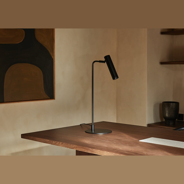 Maru Table Lamp in matt black on a walnut desk with an abstract artwork on the wall