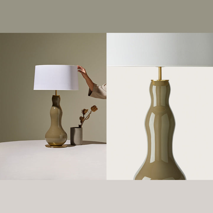 Melly Table Lamp on a white table with dried flowers, beside a close-up of its glossy olive glass base