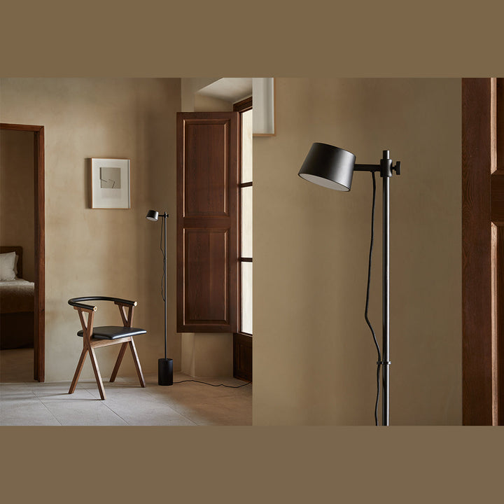 Black floor lamp beside a wooden chair in a plastered hallway, with a close-up of the head