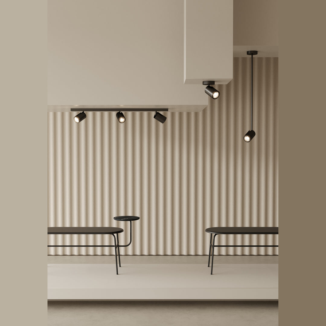 Noon Spots on a ceiling track and a single drop rod above benches against a ribbed wall