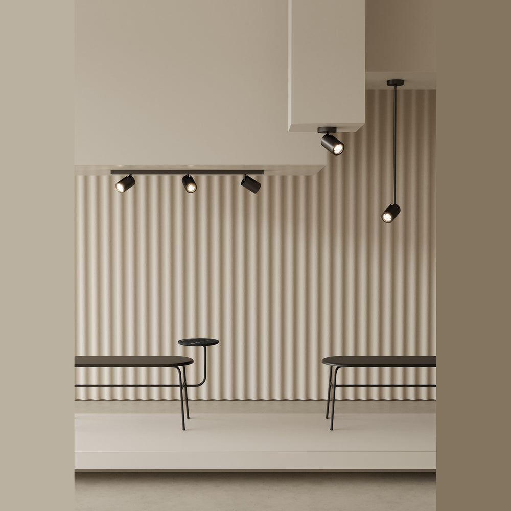 Noon T Spot hanging beside track spotlights above benches against a fluted wall