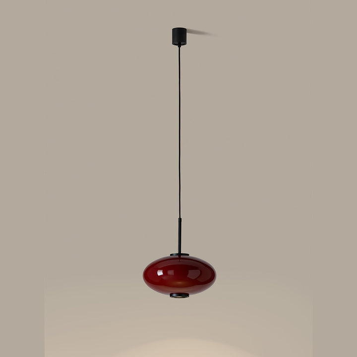 Ovalo Pendant Lamp in red glass, lit and casting a pool of light below
