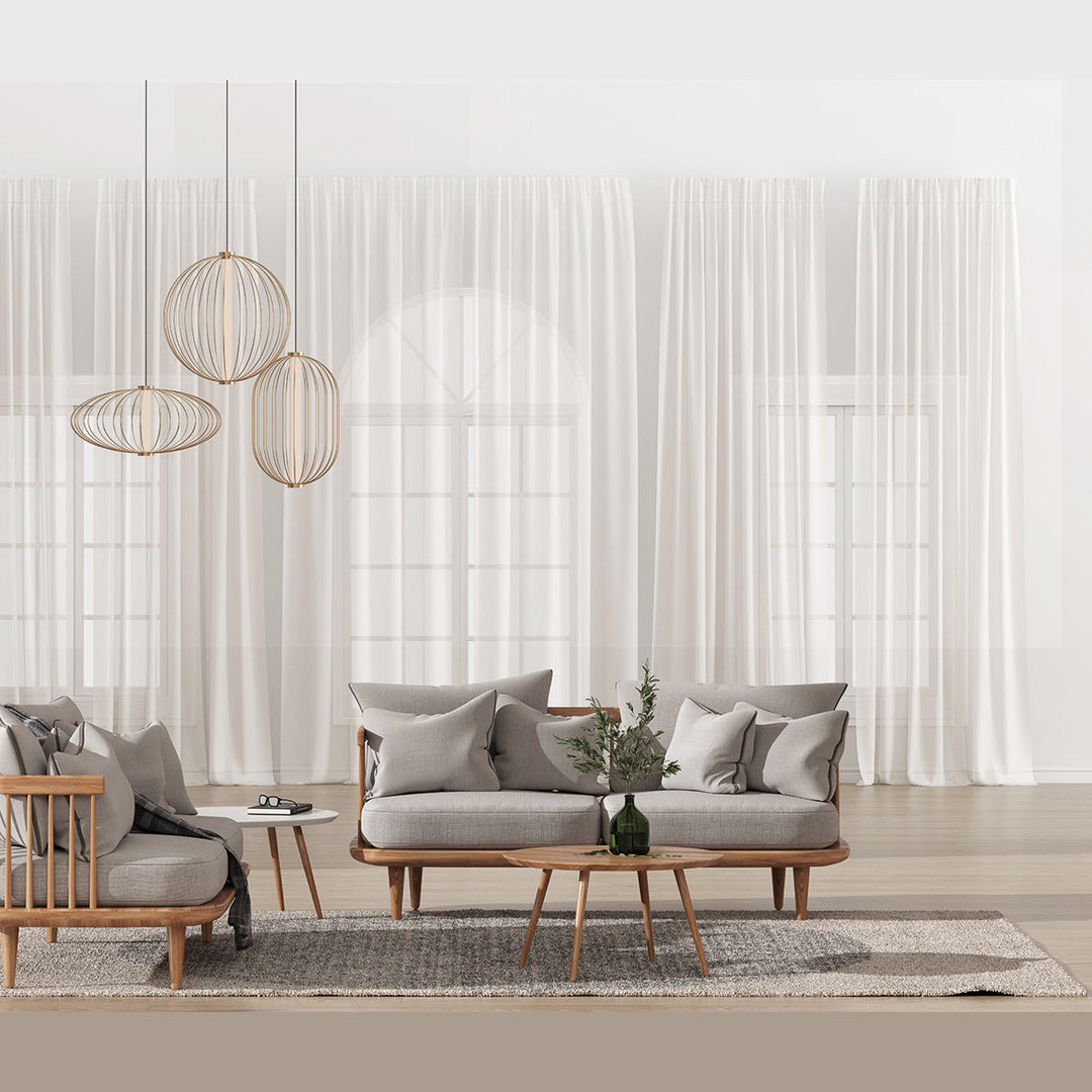 Pale gold cage pendants grouped above a grey sofa and wood coffee table with sheer curtains