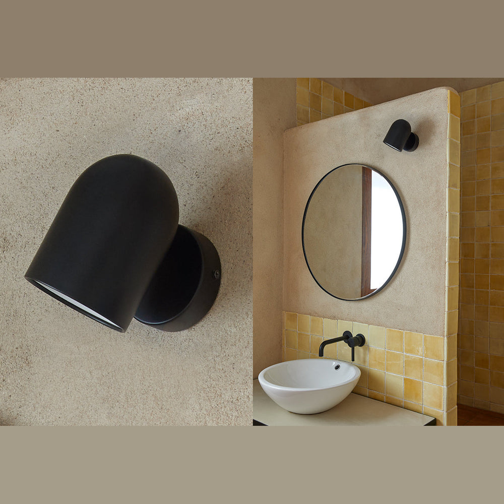 Pipe Wall Lamp on a plaster wall, and mounted above a round mirror and vessel sink in a tiled bathroom