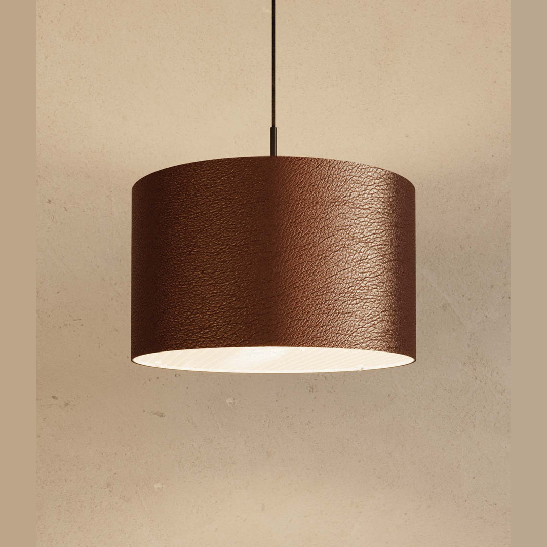 Close-up of Rems Pendant in brown leather, lit from below against a plaster wall