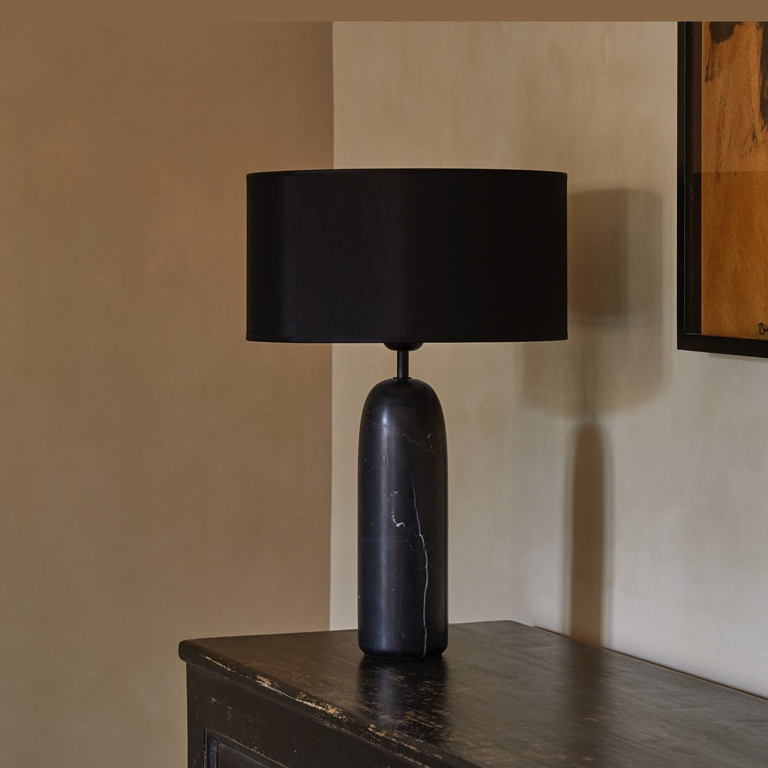 Shin Table Lamp on a dark wooden sideboard against a warm plaster wall beside framed art
