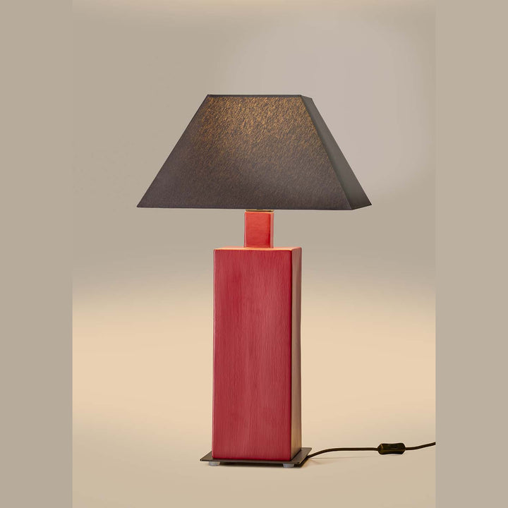 Syal Table Lamp lit, red ceramic base with a dark grey pyramid shade