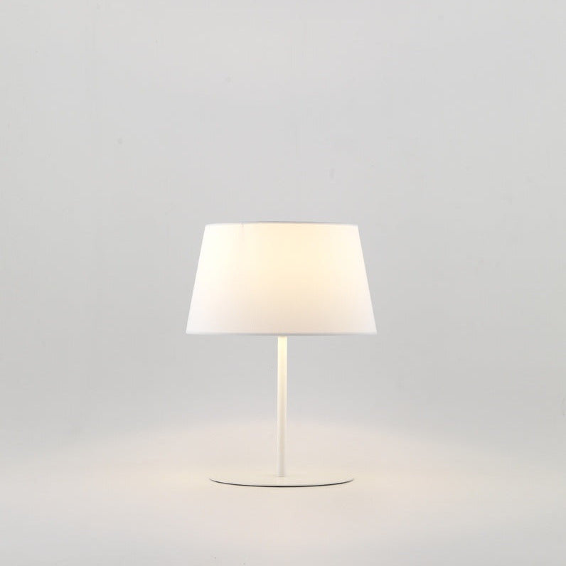 Tex Table Lamp in Matt White with tapered white shade, lit with a warm glow