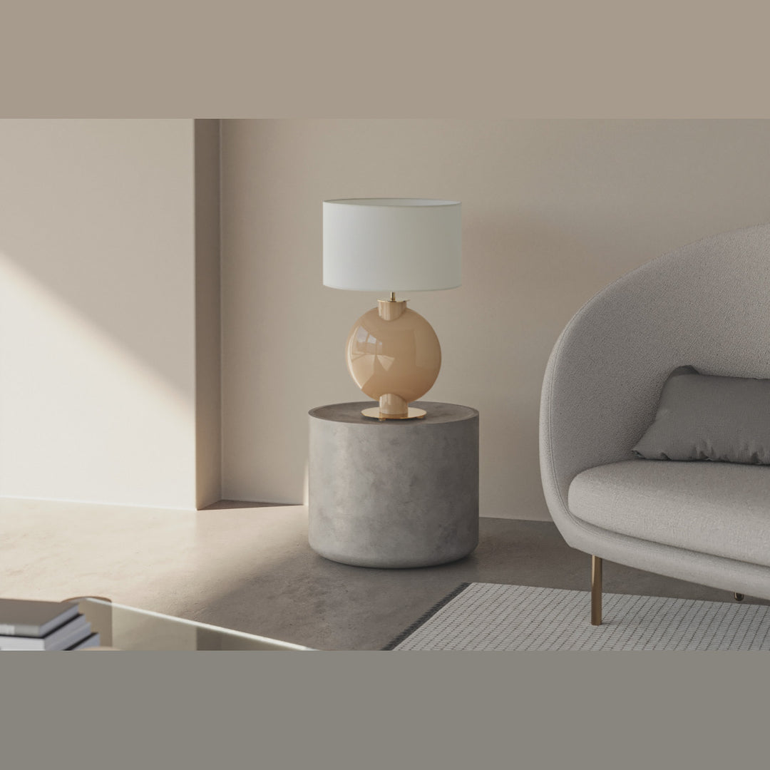 Tilla Table Lamp in nude glass lit on a stone side table beside a curved boucle sofa